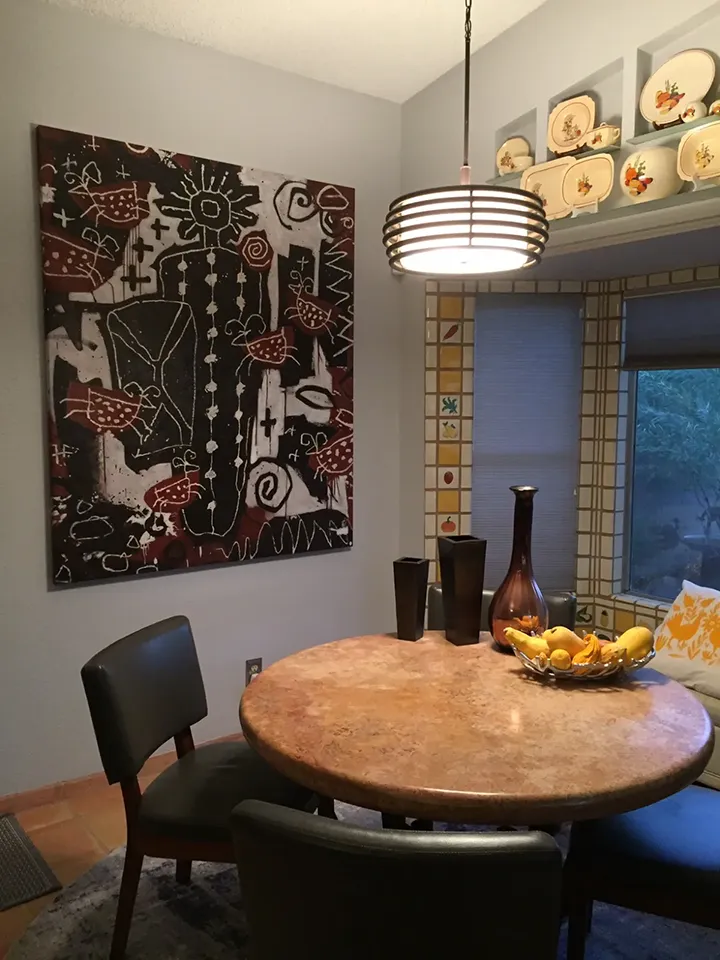 Large 60x48 inch abstract oil painting with black, white, and burgundy tones installed in a small dining room above a round stone table, creating a strong focal point without overwhelming the space