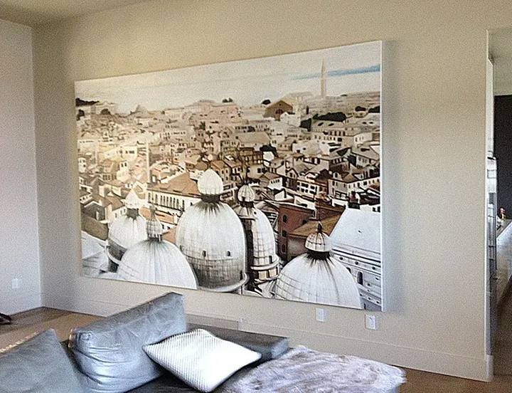 Extra-large horizontal oil painting of Venice domes and rooftops installed 8-10 inches above a grey leather sectional sofa, spanning approximately two-thirds of the sofa width in a modern living room with beige walls